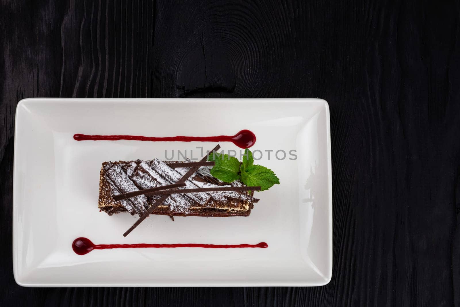 Chocolate cake decorated with mint leaves on black background