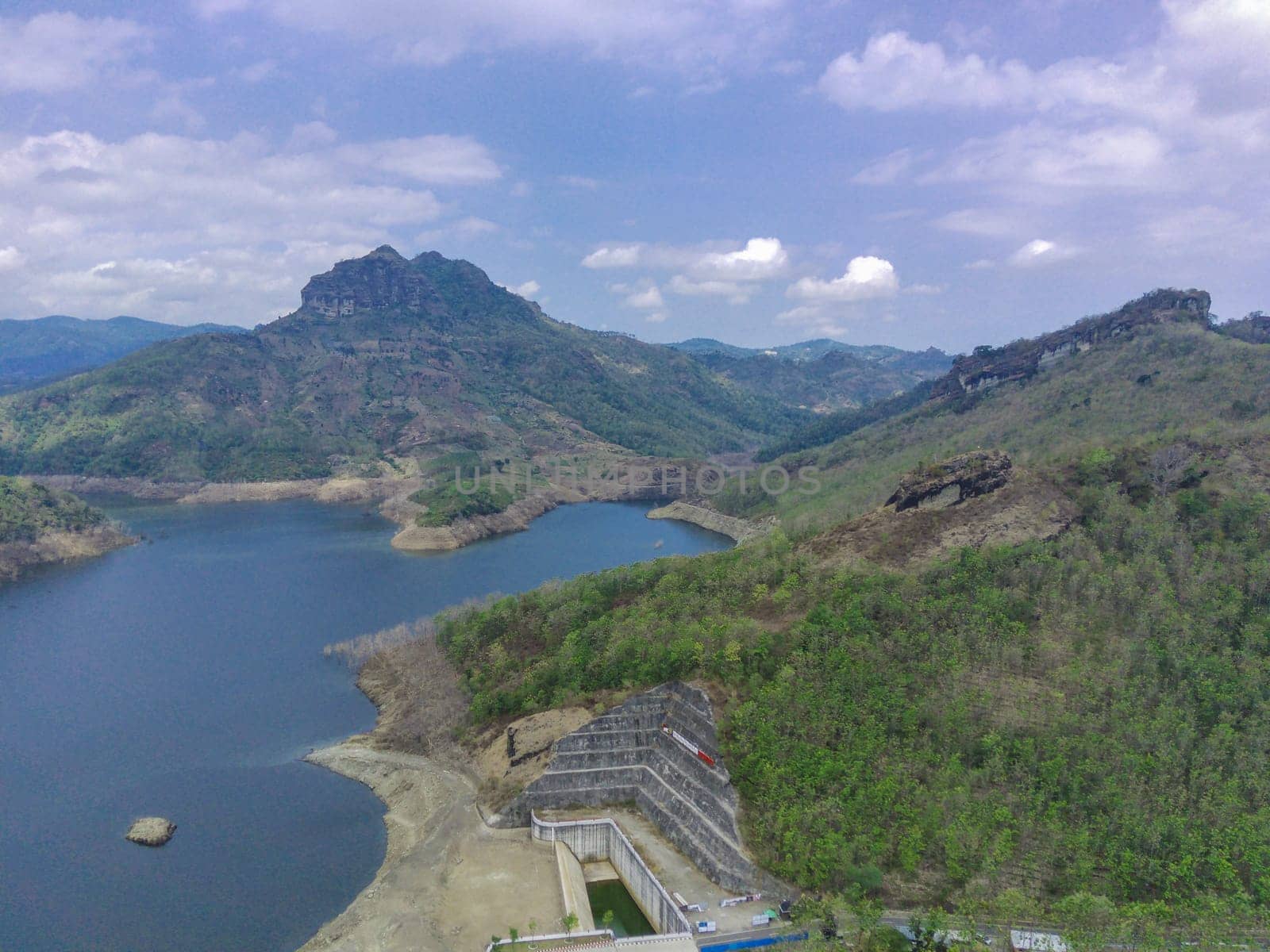 Aerial view of water dam against the hills and cloudy sky