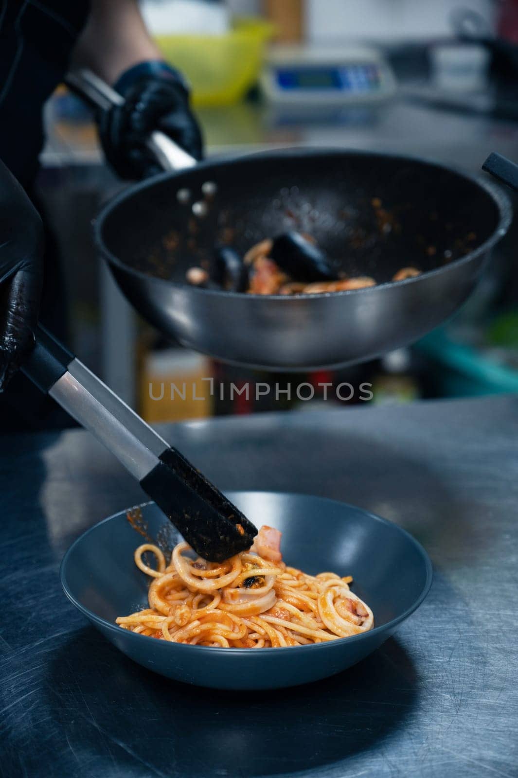 Chef preparing Seafood Pasta with mussels with basil and tomato in black plate