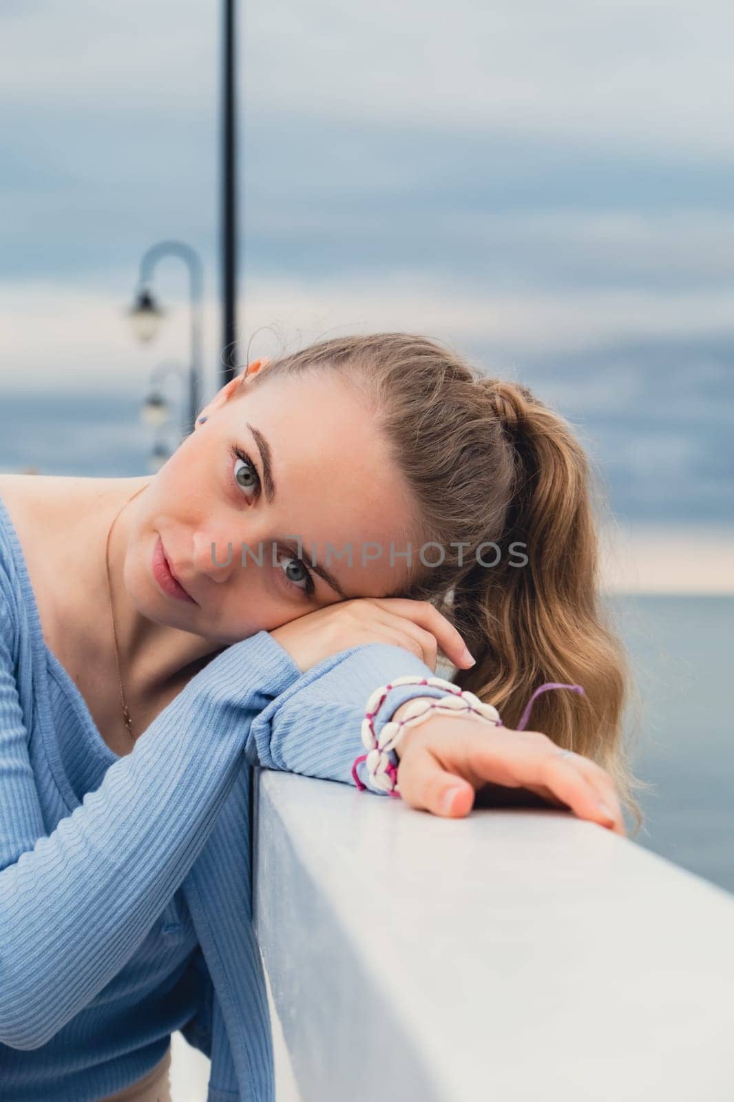 Young woman standing on wooden pier blurred beachside background. Attractive female enjoying the sea shore travel and active lifestyle concept. Springtime. Wellness wellbeing mental health inner peace Slow life digital detox