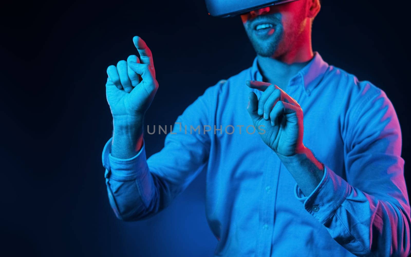 Virtual glasses gaming experience. Neon lighting. Young european man is in the dark studio.