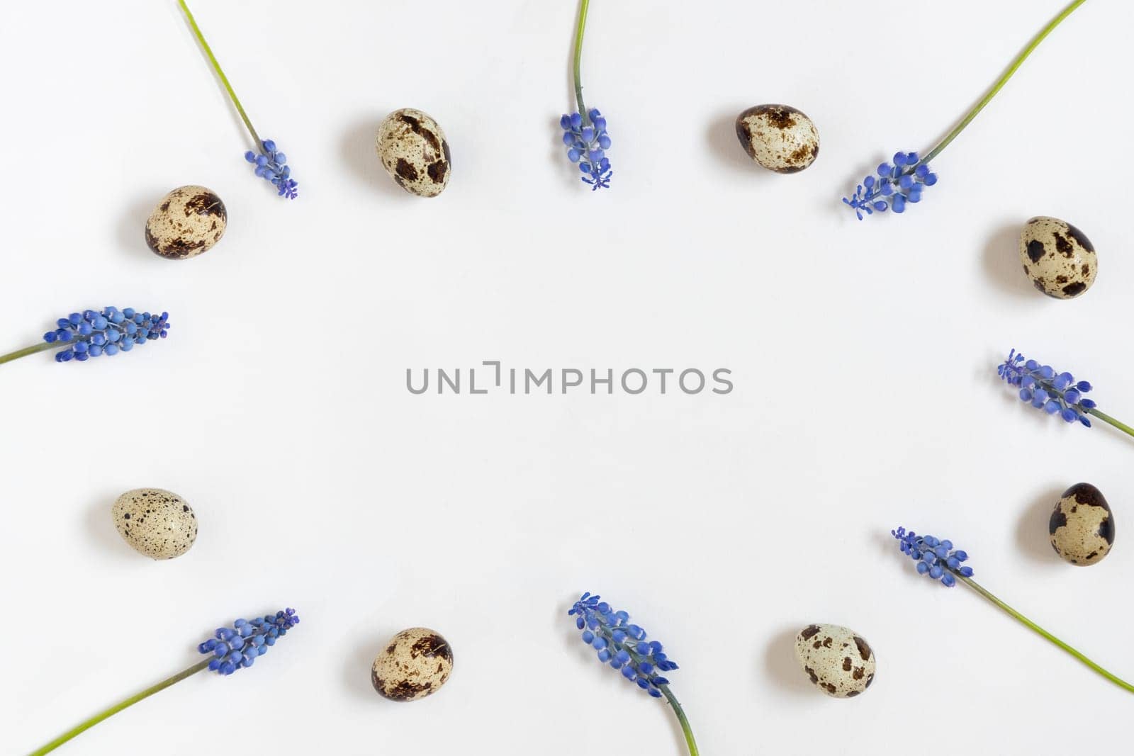 Easter quial eggs and fresh spring flowers. White textile background. Happy easter concept, top view, space for text.