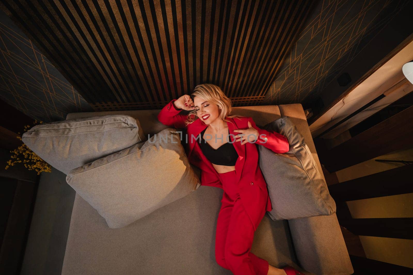 a beautiful girl dressed in a red formal suit posing in a modern interior by Lobachad