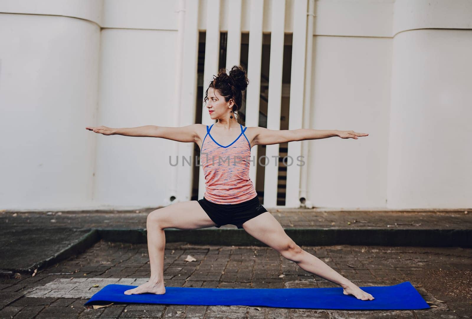 Girl practicing yoga Warrior II pose outdoors. Latin woman doing yoga warrior pose outdoors. Young woman doing yoga virabhadrasana II outdoors