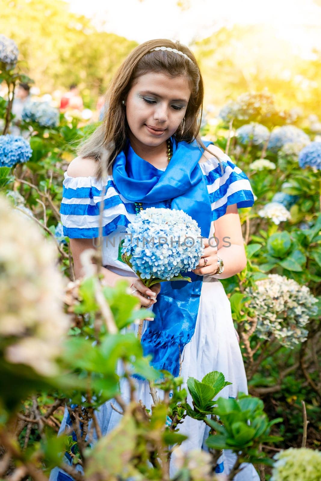 Beautiful Nicaraguan woman in national folk costume holding flowers in a nursery. Portrait of girl in traditional Central American folk costume holding flowers in a nursery. Nicaraguan folk costume by isaiphoto