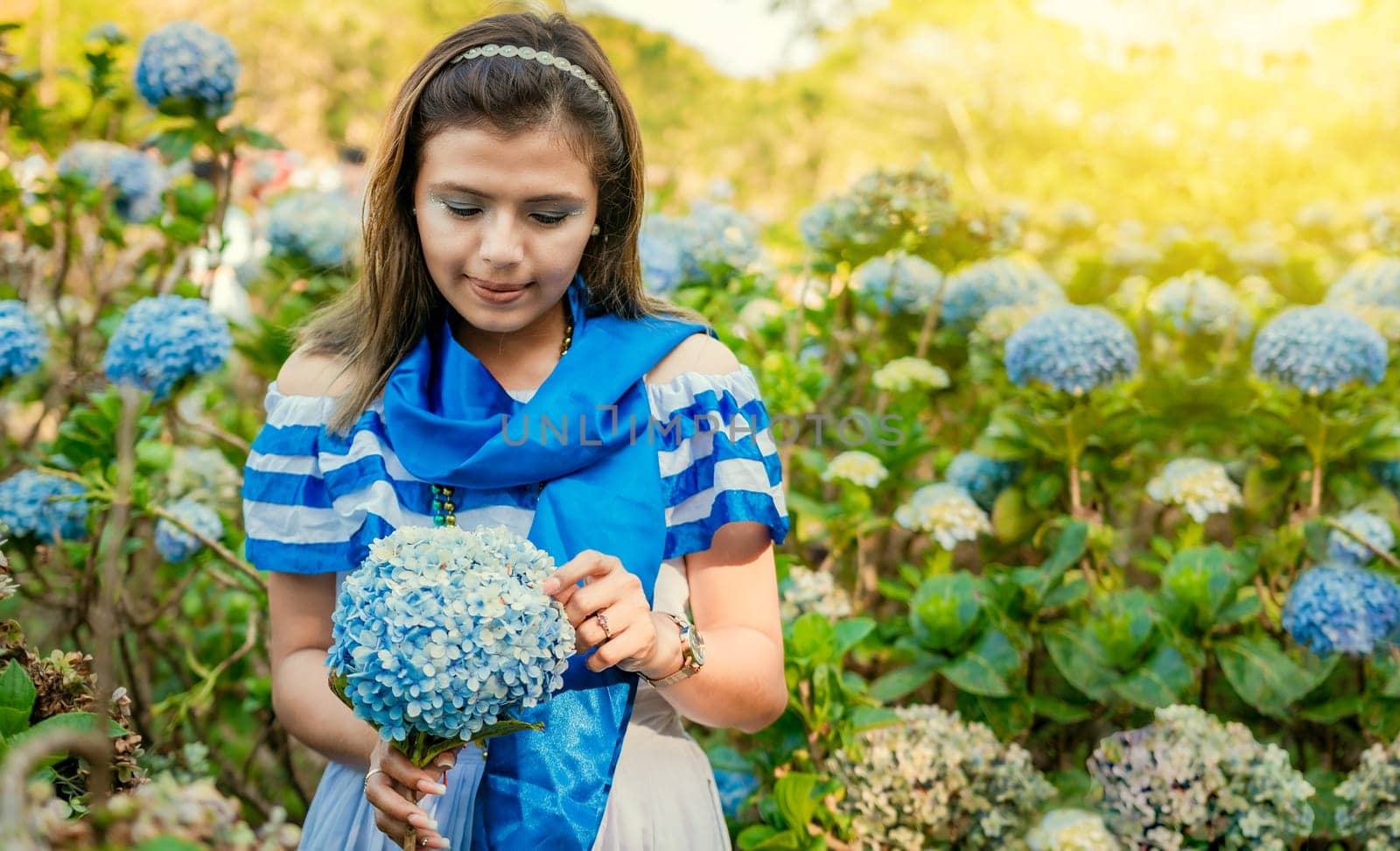 Nicaraguan girl in traditional folk costume holding flowers in a nursery. Beautiful Nicaraguan woman in national folk costume holding flowers in a nursery. Nicaraguan folk costume by isaiphoto