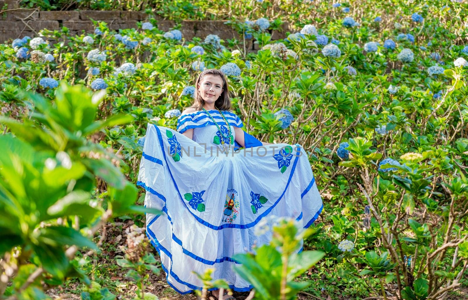 Portrait of young Nicaraguan woman in traditional folk costume in a field of flowers, Nicaraguan woman in traditional folk costume in a field of flowers by isaiphoto