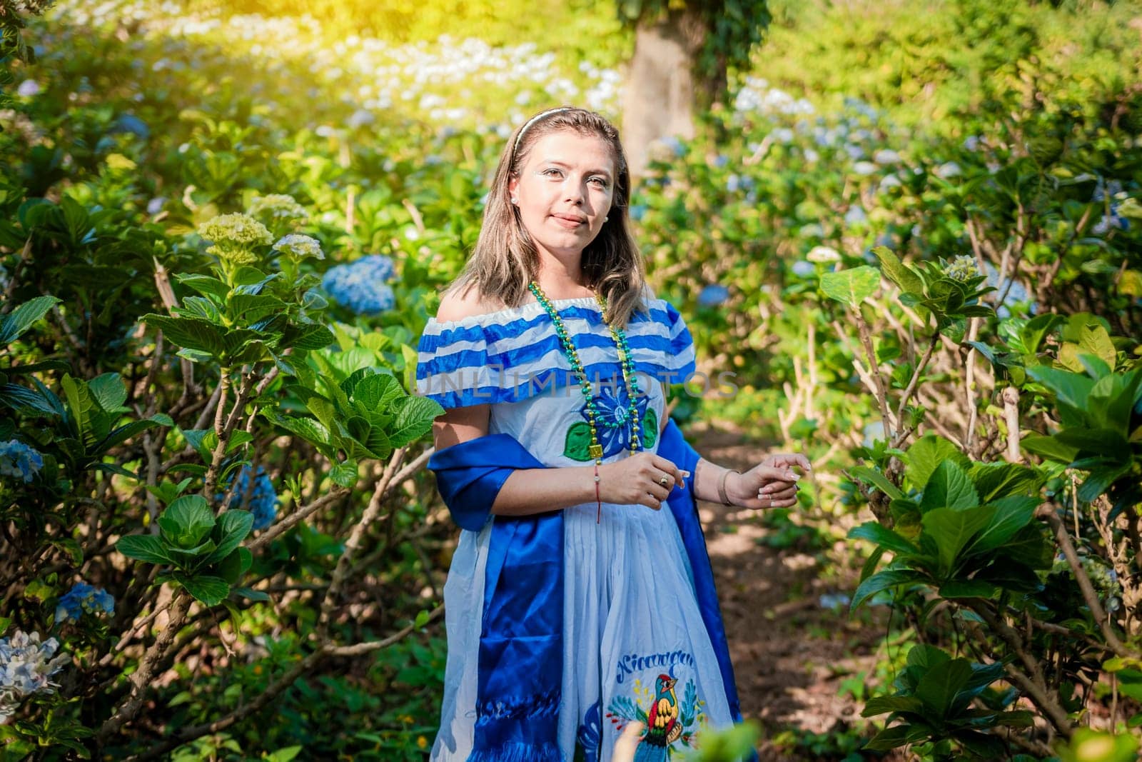 Smiling woman in national folk costume in a field surrounded by flowers. Nicaraguan national folk costume, Young Nicaraguan woman in traditional folk costume in a field of Milflores