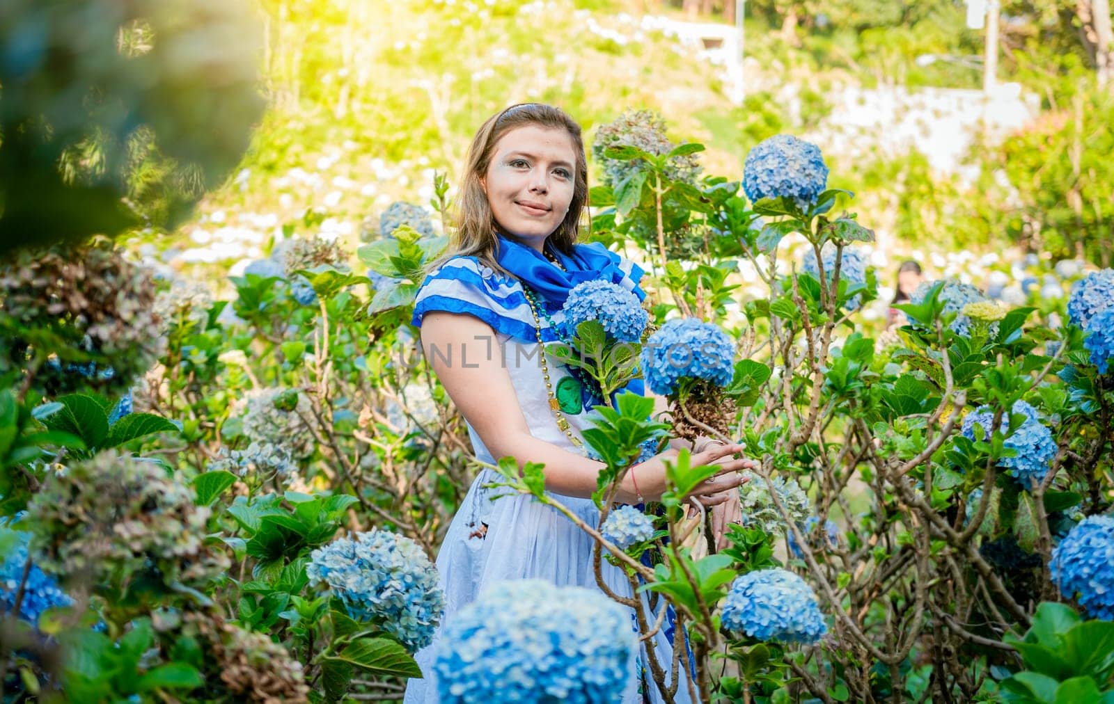 Portrait of beautiful woman in national folk costume in a field of flowers. Nicaraguan national folk costume, Young Nicaraguan woman in traditional folk costume holding flowers in the field