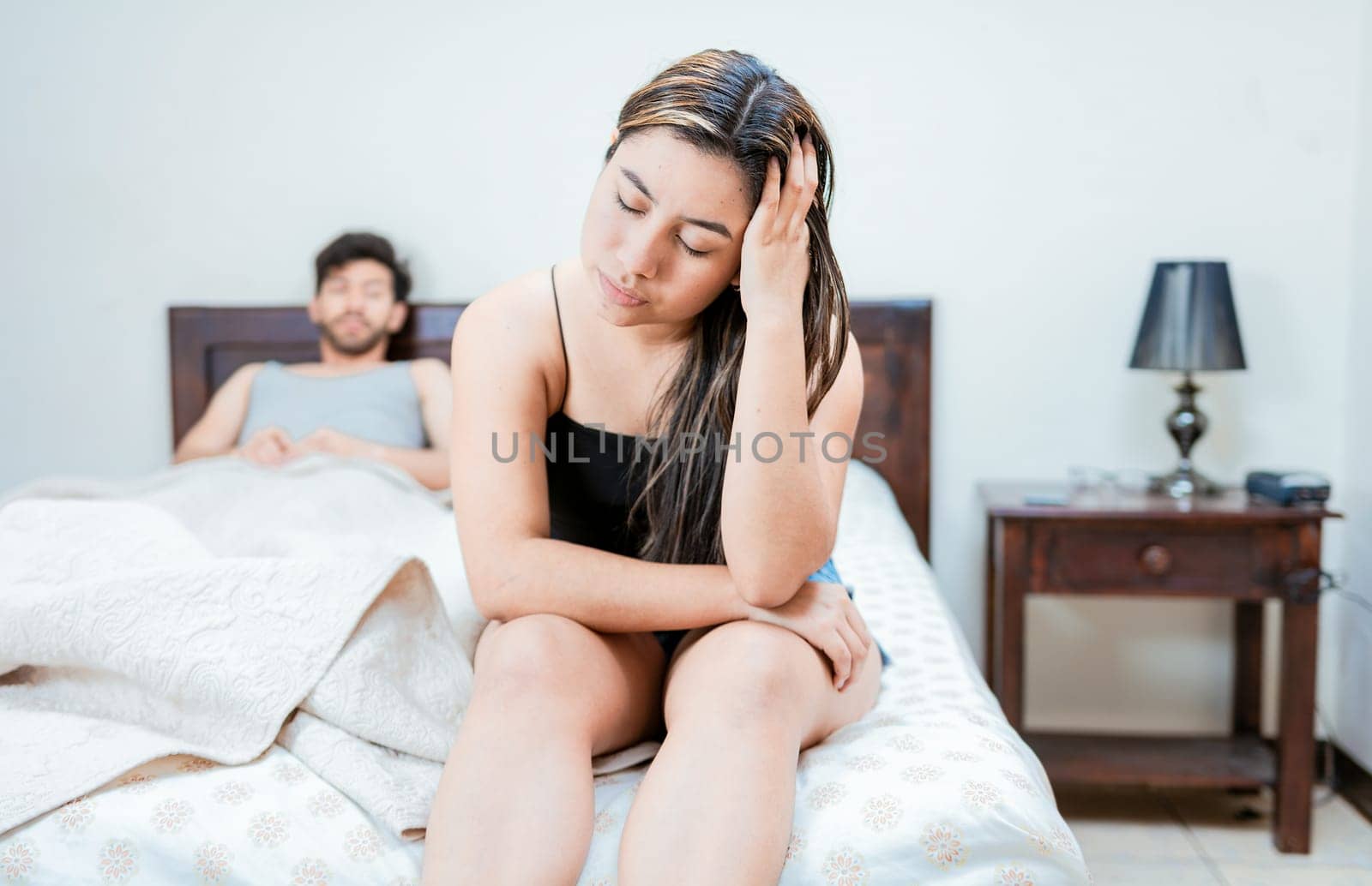Wife on the edge of the bed arguing with her husband. Upset woman arguing with her husband in bed. Concept of couple problems in bed by isaiphoto
