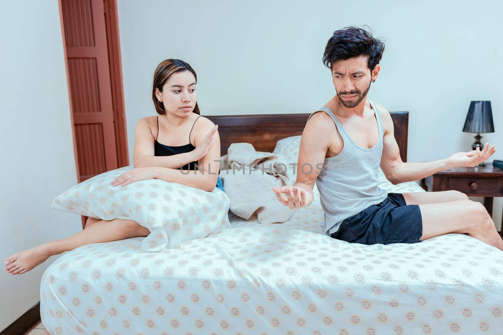 Man arguing with his wife in the bedroom bed. Upset wife ignoring husband in bed. young couple arguing in the bedroom. Concept of couple crisis in bed