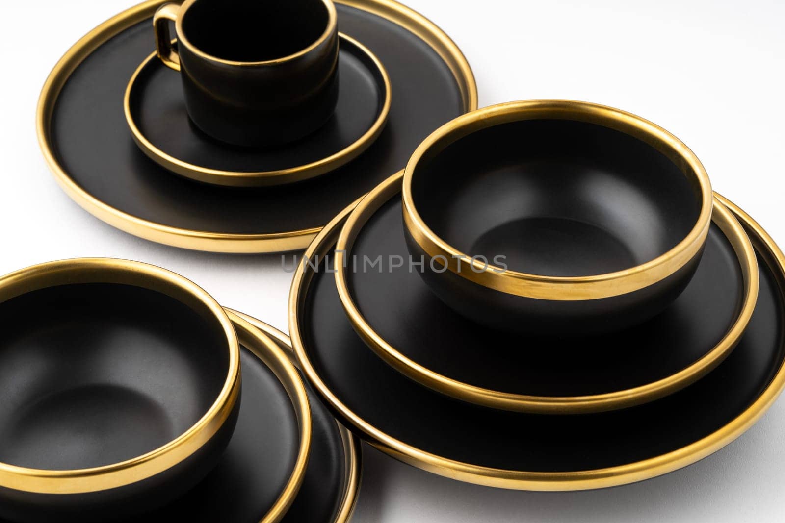 A set of black and golden ceramic plates and cup on a white background