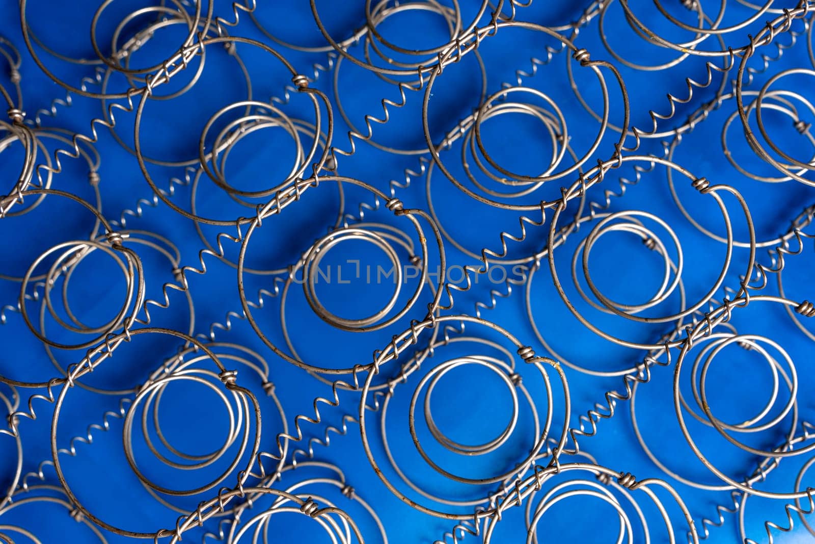 Abstract background The internal structure of a spring mattress. close-up of an old spring mattress on a blue background. Spring block. Sofa and bed. defocusing. top view