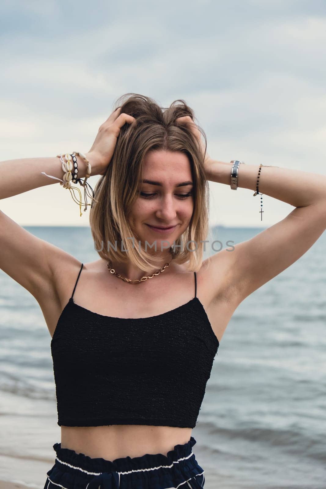 Young woman standing on blurred beachside background. Attractive female enjoying walking the sea shore. travel and active lifestyle concept. Springtime. Relaxation, youth, love, lifestyle solitude with nature. Wellness wellbeing mental health inner peace Slow life digital detox