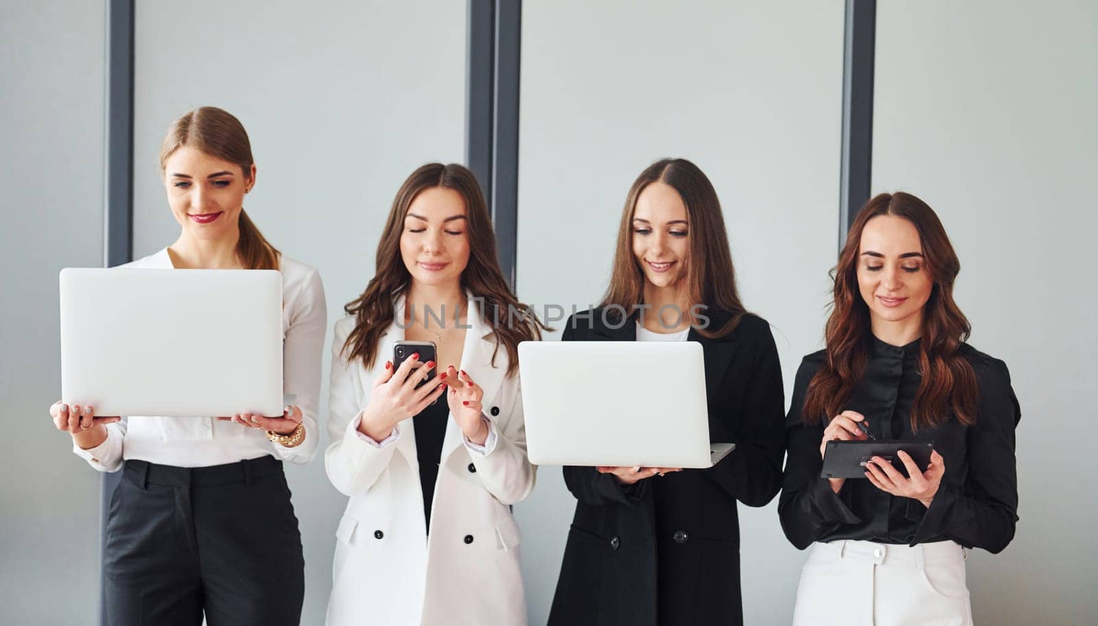 Group of adult women that in formal clothes is indoors in the office together.