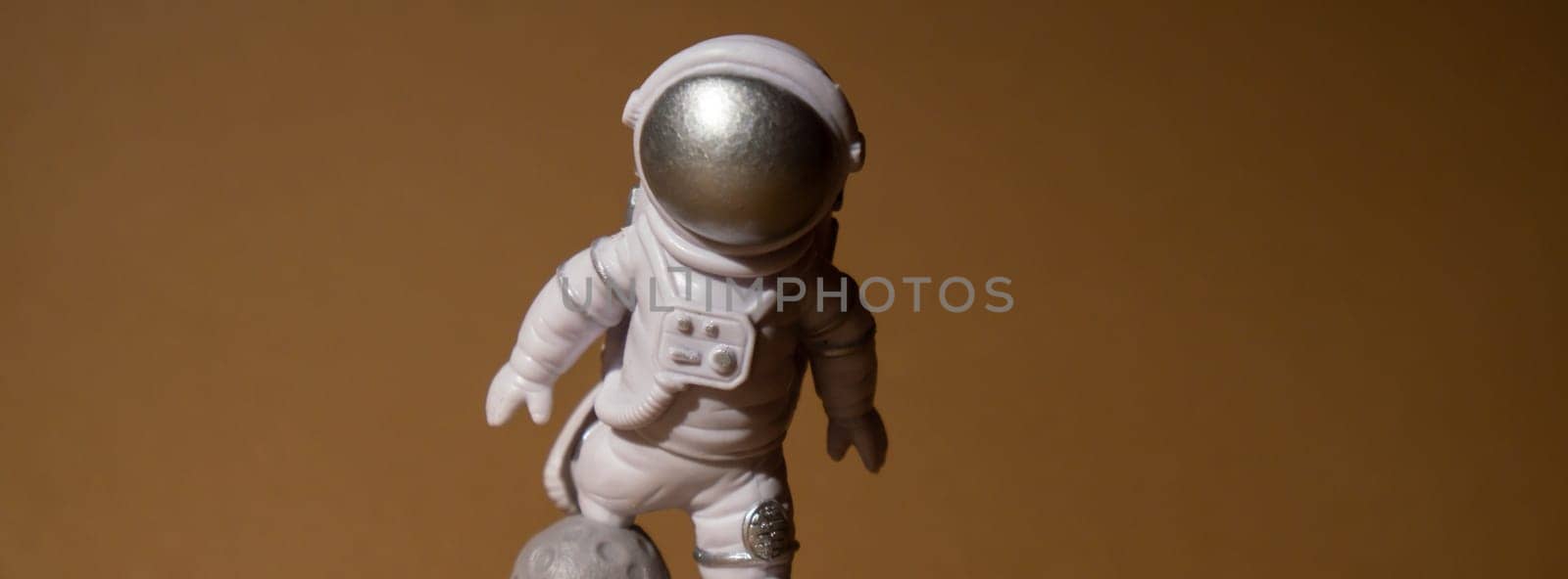 Plastic toy figure astronaut on beige neutral background Copy space. Concept of out of earth travel, private spaceman commercial flights. Space missions and Sustainability