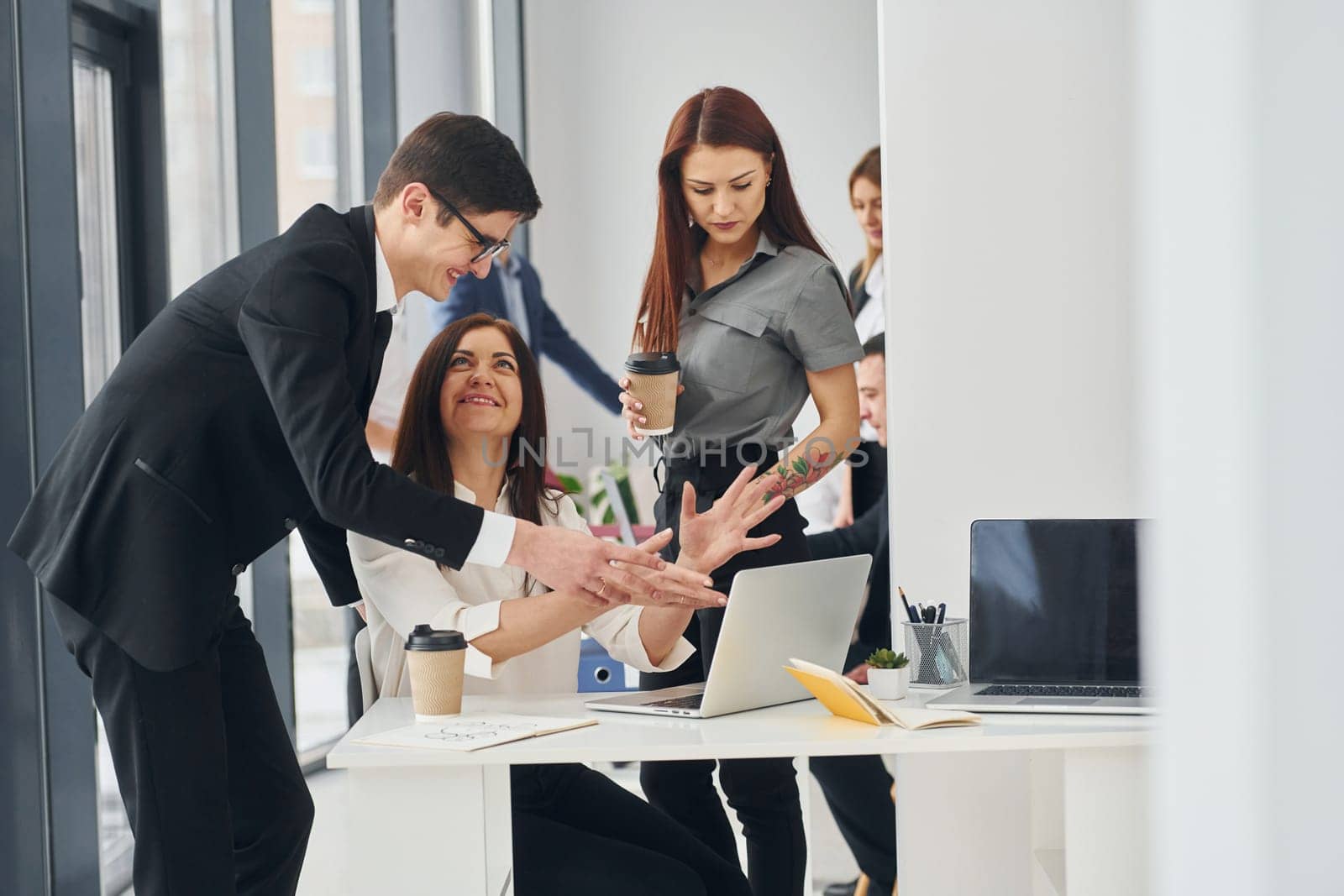 Works by using laptop. Group of people in official formal clothes that is indoors in the office.