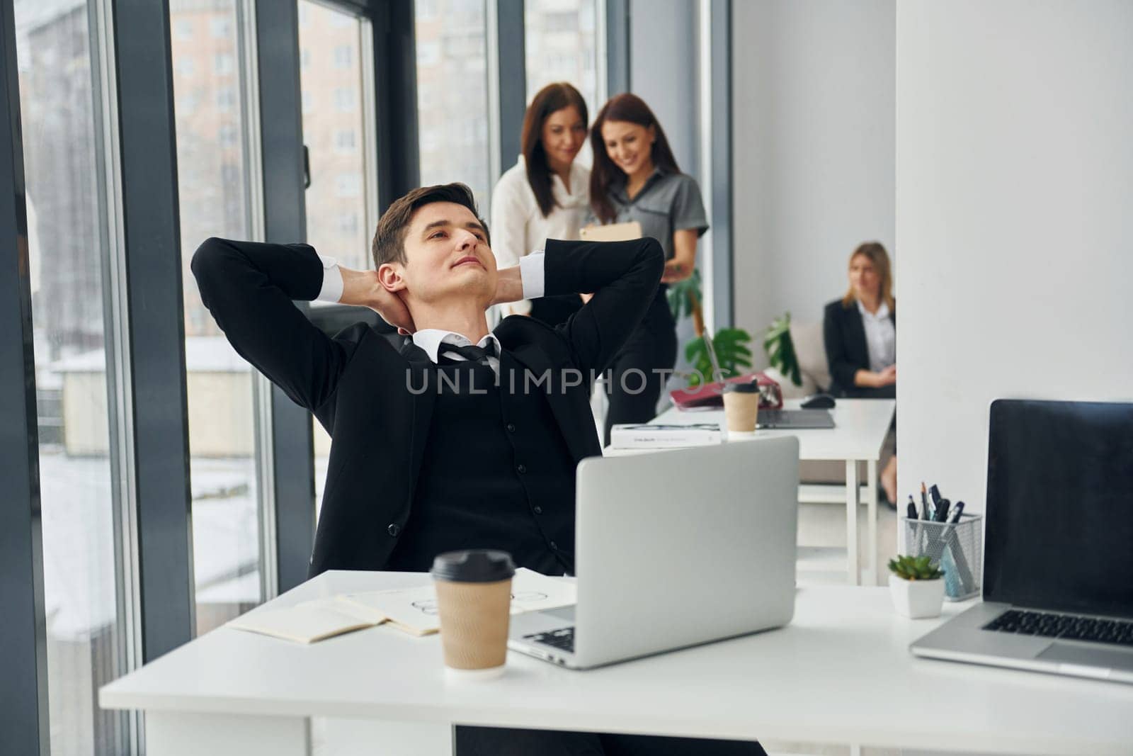 Man takes a break. Group of people in official formal clothes that is indoors in the office by Standret