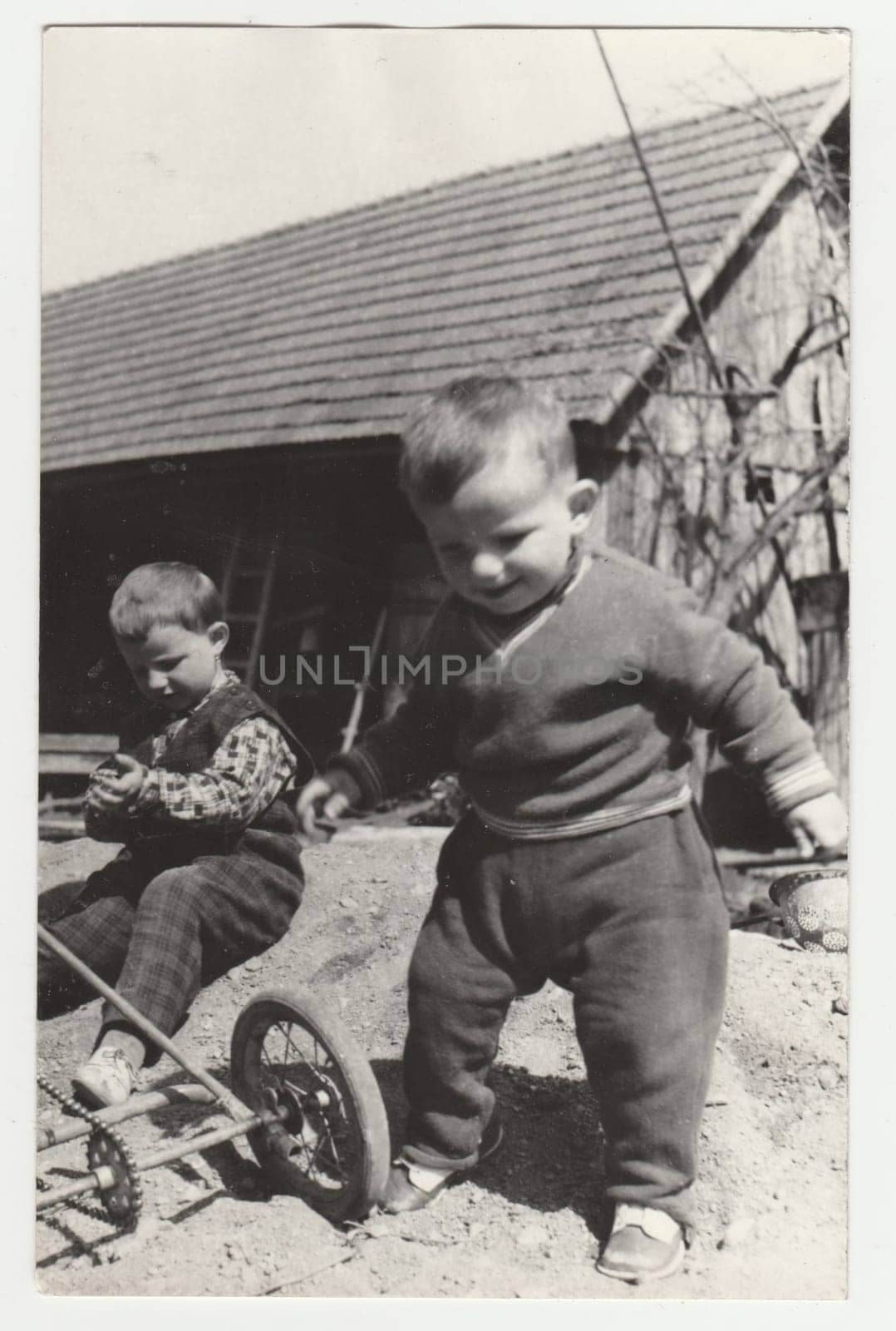 Vintage photo shows two small boys play in the backyard. Retro black and white photography. Circa 1970s. by roman_nerud