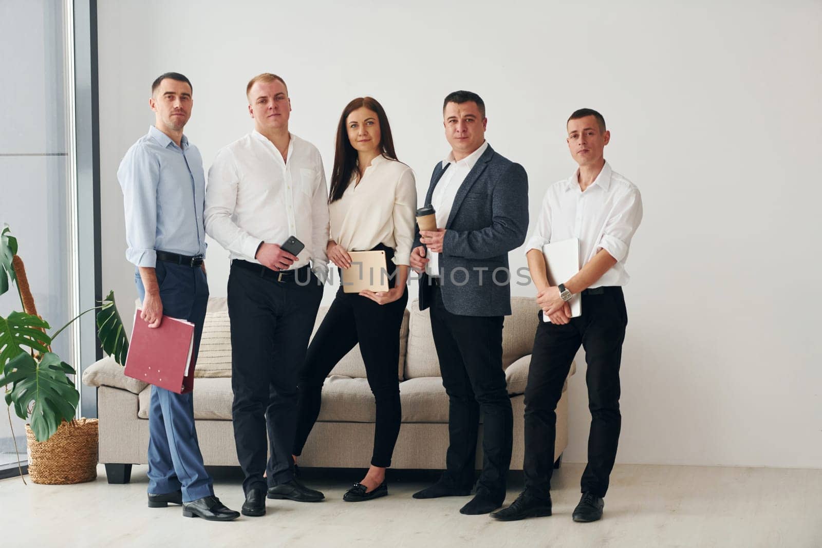 Group of office workers in formal official clothes is together indoors by Standret