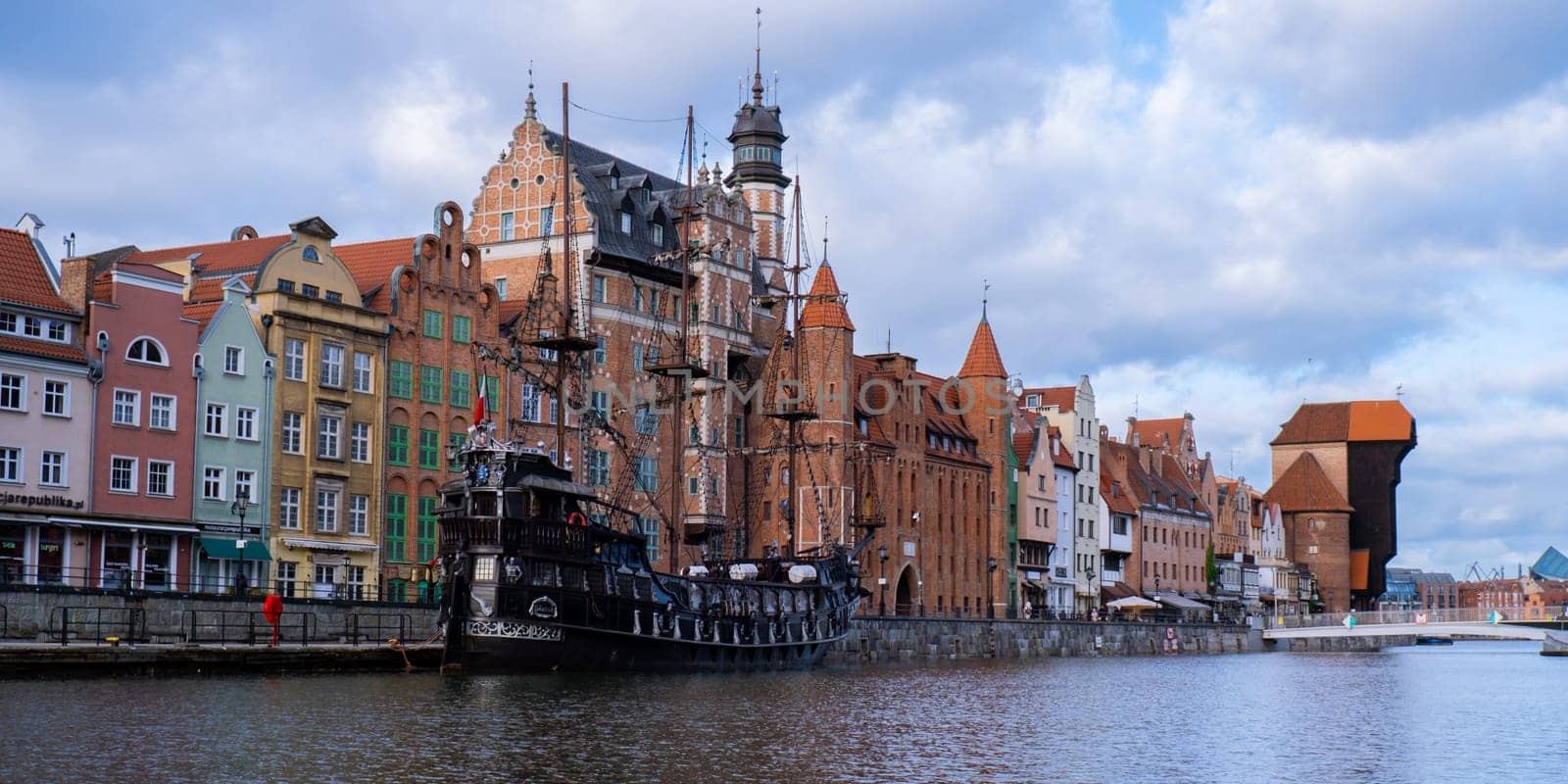 Beautiful old town of Gdansk over Motlawa river Vintage ship pirate caravels sailing on Motlawa river with historic port Crane in Old Town on background. Gdansk, Poland. This ship imitating XVII century galleon is big tourist attraction of Tri city in Poland. Travel destination