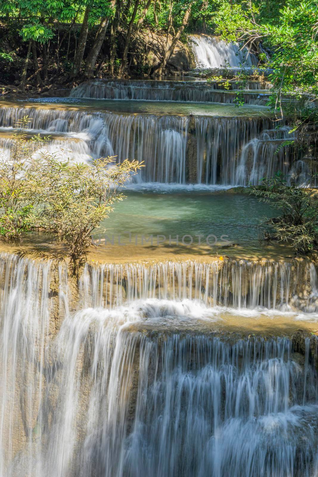 The clear water of the waterfall circulates through the yellow limestone. Huai Mae Kamin Waterfall Viewpoint, Kanchanaburi Province