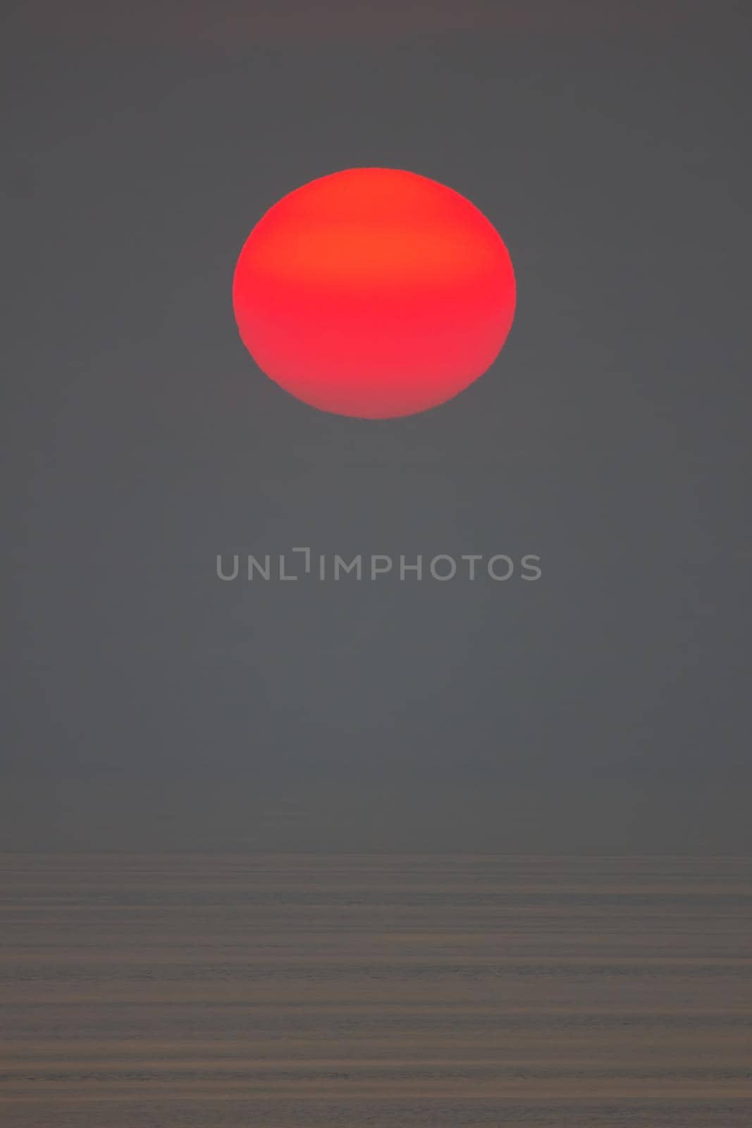 The sun is falling into the sea. It is colour orang The sky and the sea is dark