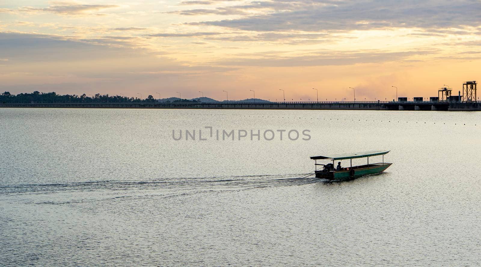 Passenger boats across the side of the dam. Evening atmosphere along the water in the dam. Sailing boat to transport people across the canal In the water storage dam