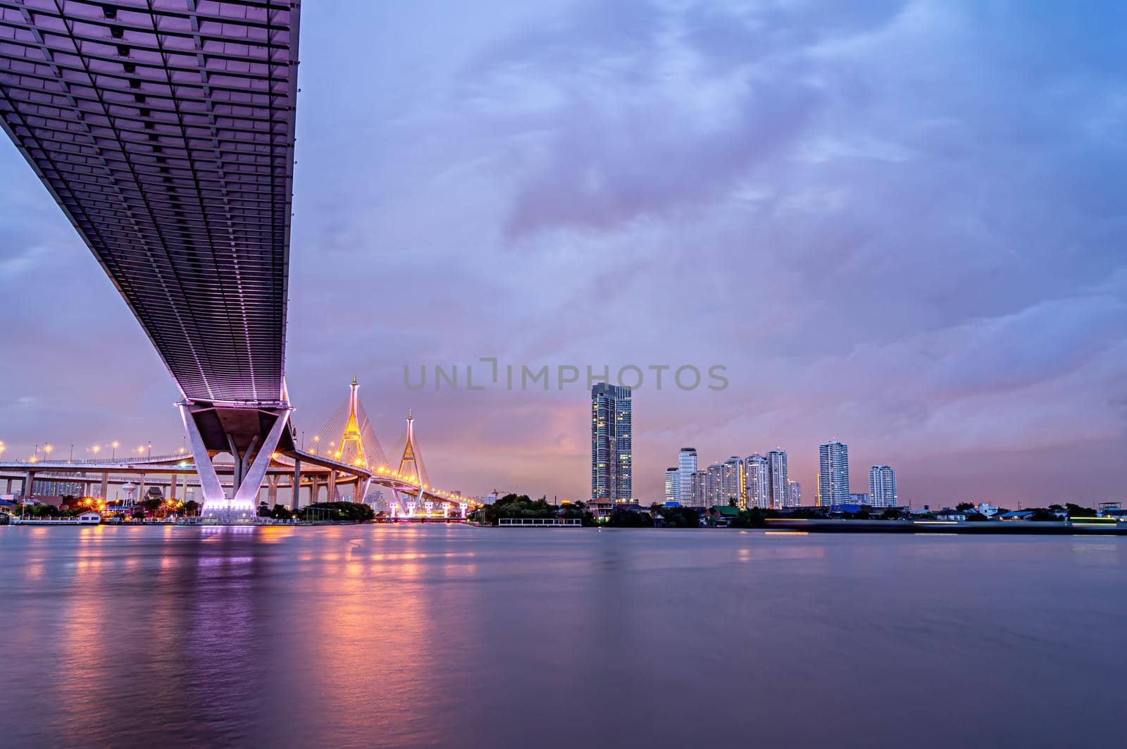 Purple led light under the bridge over the river On a cloudy day in the sky. Bhumibol Bridge, Samut Prakan, Thailand