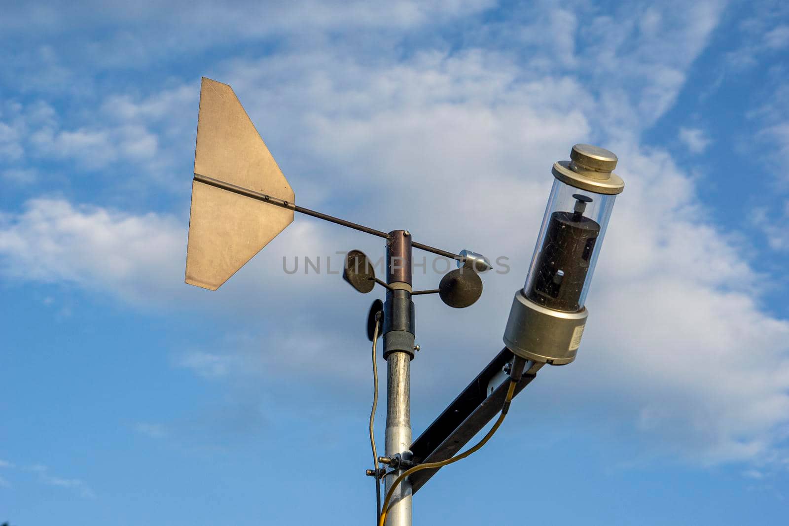 Wind speed measuring device The background is a sky with white fluffy clouds.