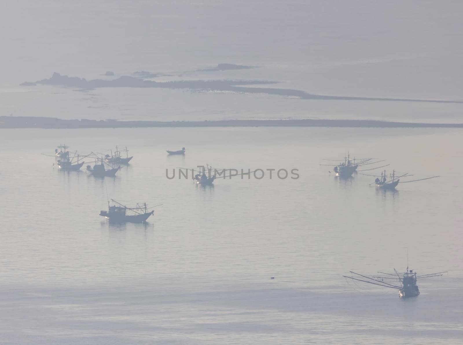 Shallow fishing boats anchor at the beach on thick fog days.	