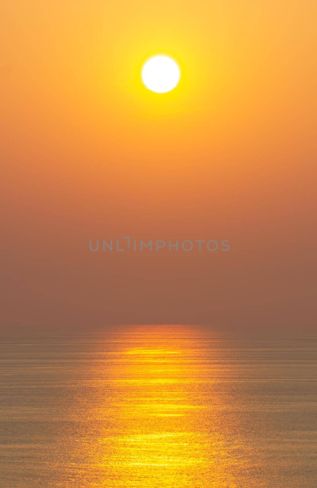 The sunset, the sea surface reflects the sunlight in gold. Clear sky, orange without clouds