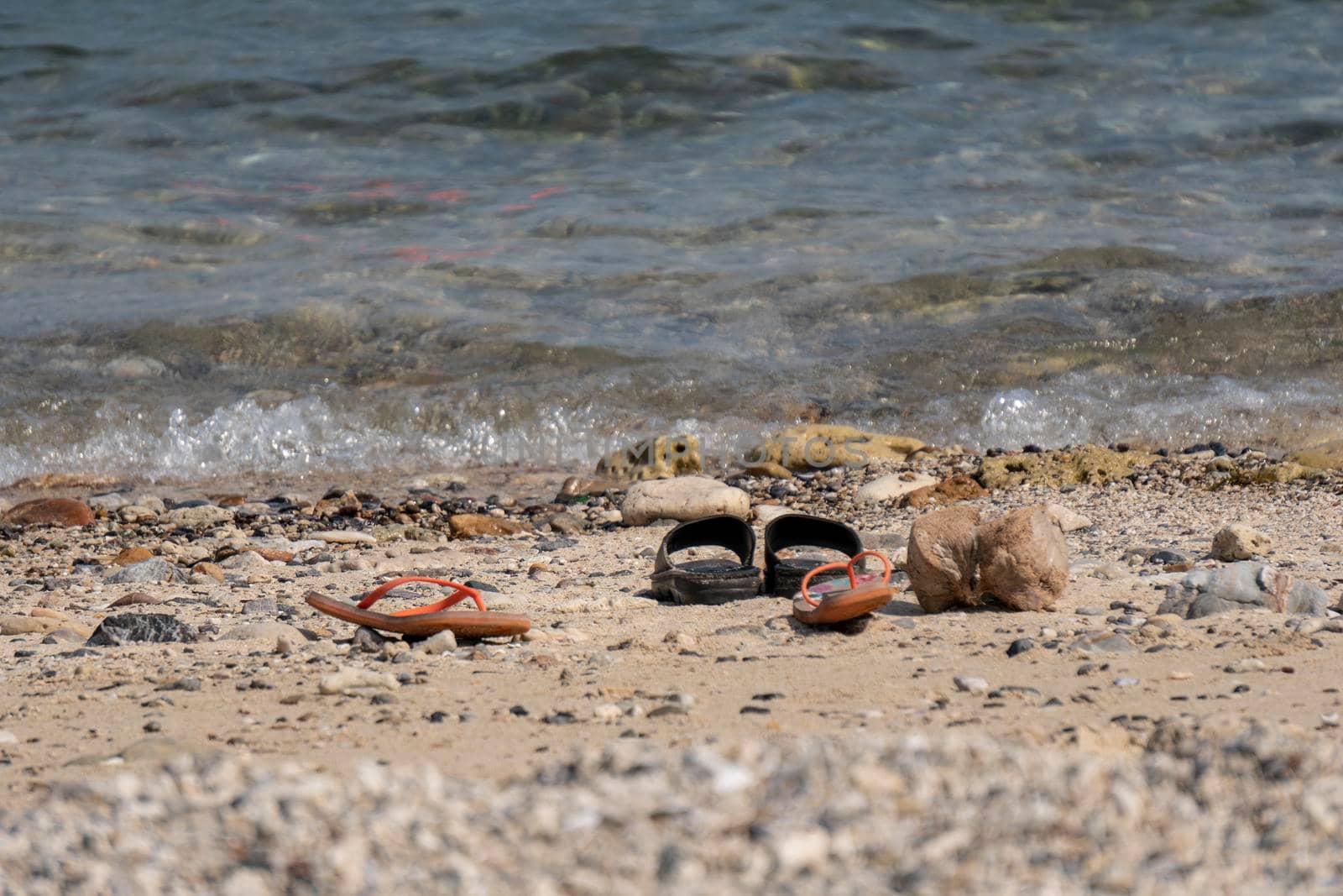 Travelers take off casual shoes on the beach by the sea to swim.