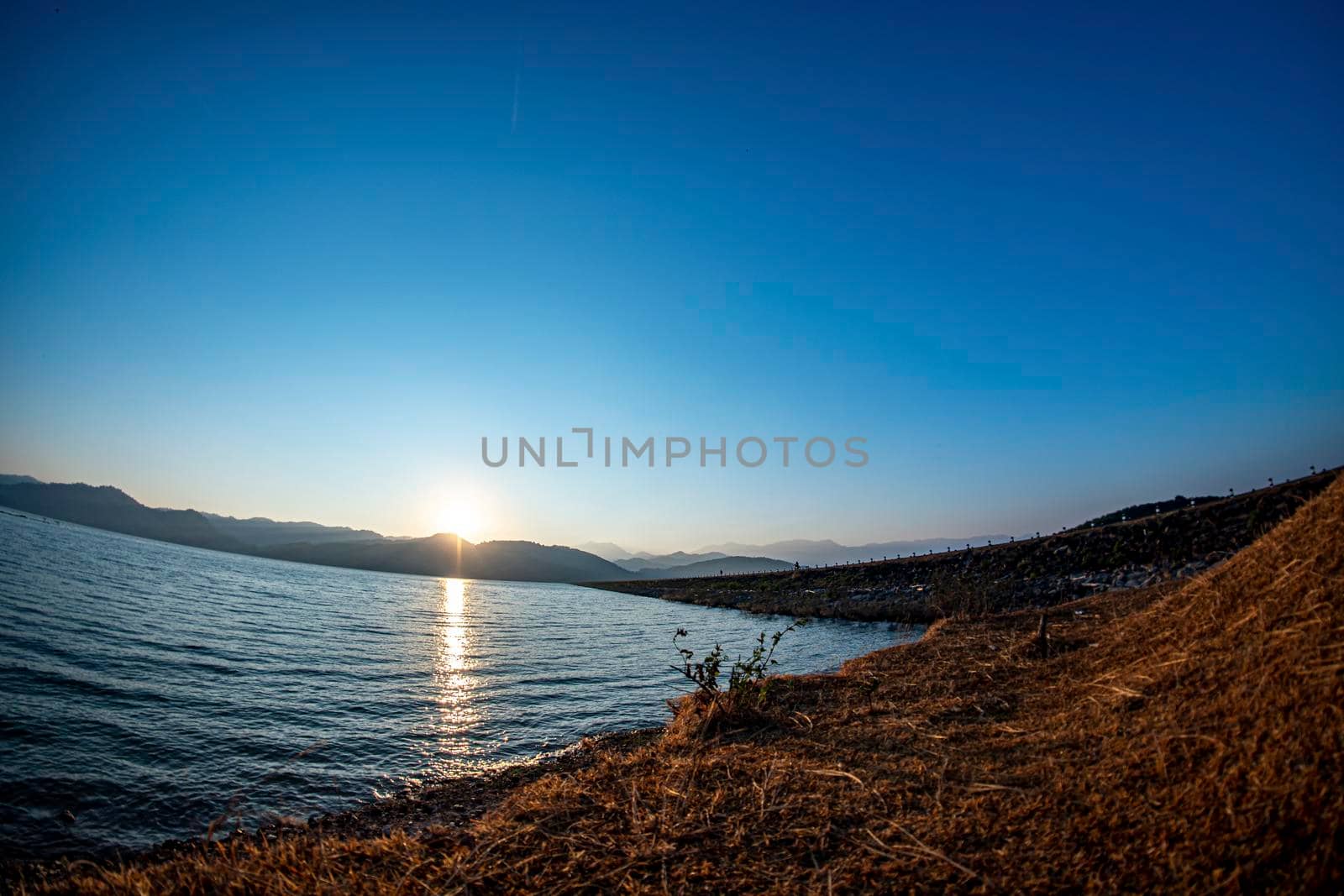 Sunrise at the reservoir, clear blue sky, wide angle from Lens Fisheye, March 9, 2019, Khlong Din Daeng Reservoir, Nakhon Si Thammarat, Thailand