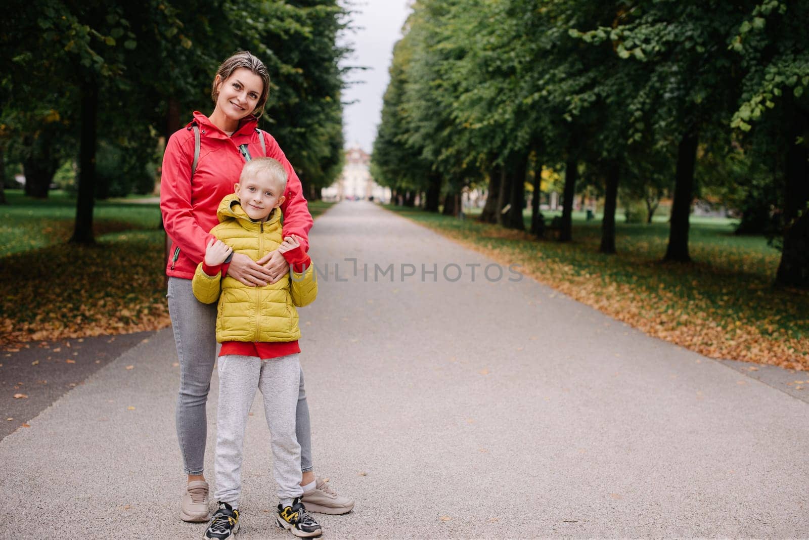 mother and son stand hugging in the park in the fall. happy mother playing with her son in the park. Mother hugs her son while standing in the forest in autumn. by Andrii_Ko