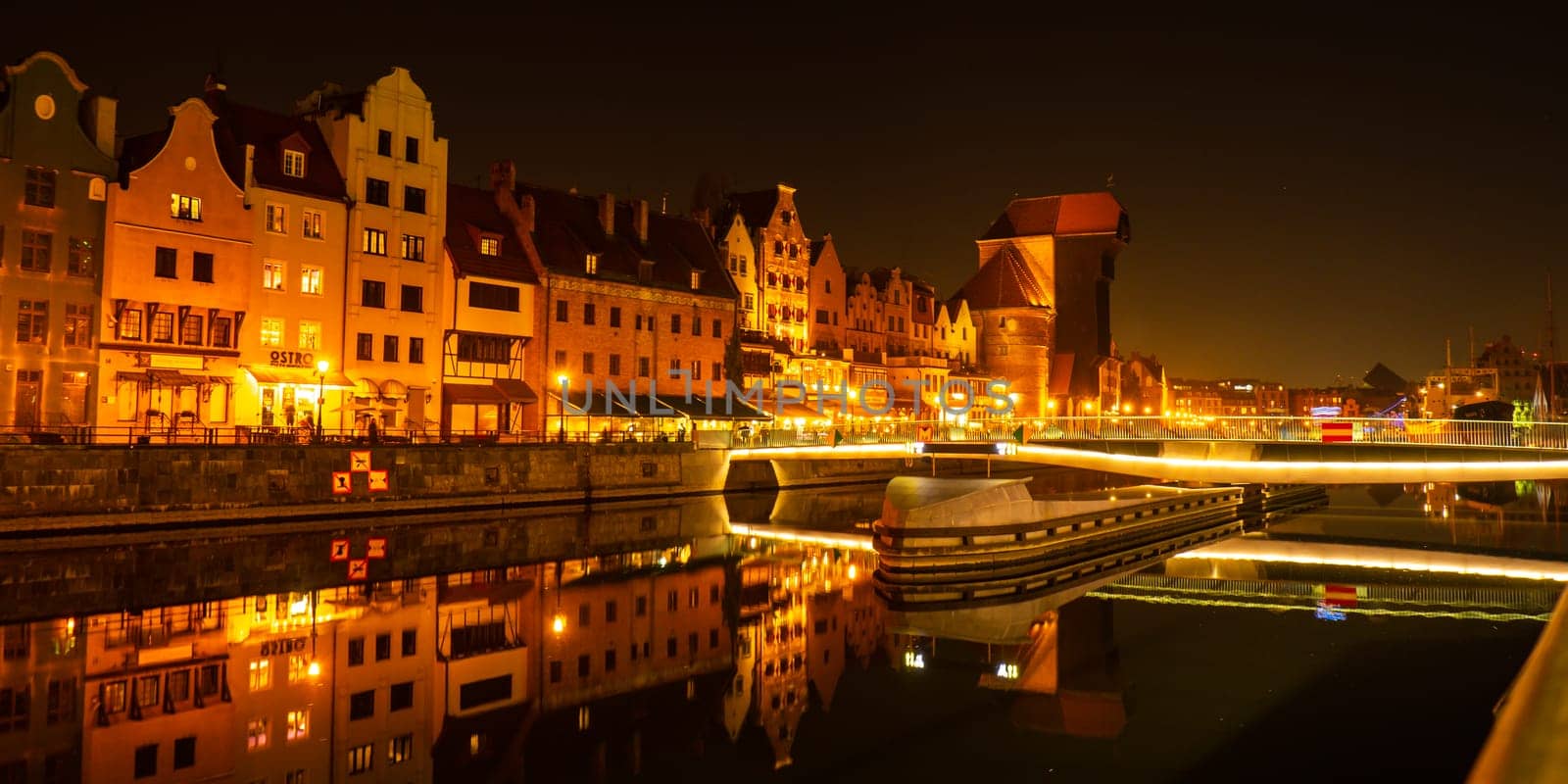 Old town in Gdansk at night. The riverside on Granary Island reflection in Moltawa River Cityscape at twilight. Ancient crane at dusk. Visit Gdansk Poland Travel destination. Tourist attraction