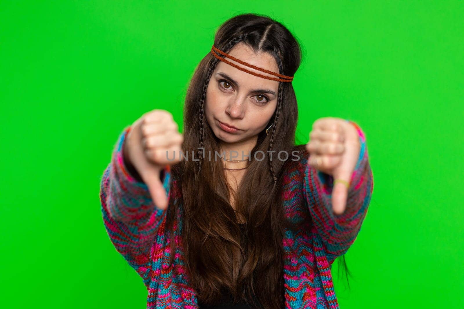 Dislike. Upset unhappy young woman showing thumbs down sign gesture, expressing discontent, disapproval, dissatisfied, dislike. Pretty hippie girl. Indoors shot on chroma key background, green screen