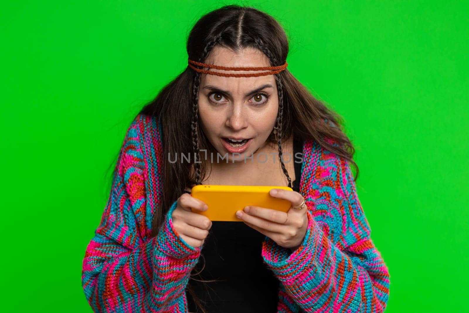 Worried funny addicted young woman enthusiastically playing racing video games on mobile phone. Happy girl using smartphone gadget app with drive simulator isolated on green chroma key background