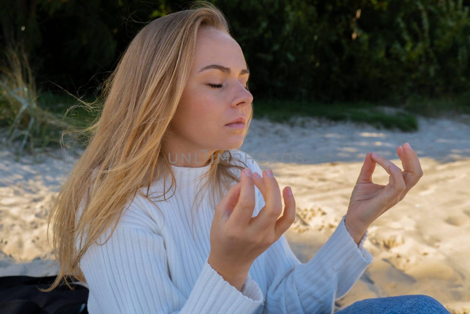 Young woman meditate on beach next to sea ocean. Breath exercises wellbeing for mental health. Breathing therapy. Balance kundalini energy every day routine practice good for woman health mindfulness. Healthy female enjoy outdoor lifestyle relaxation exercise and meditation on beach vacation