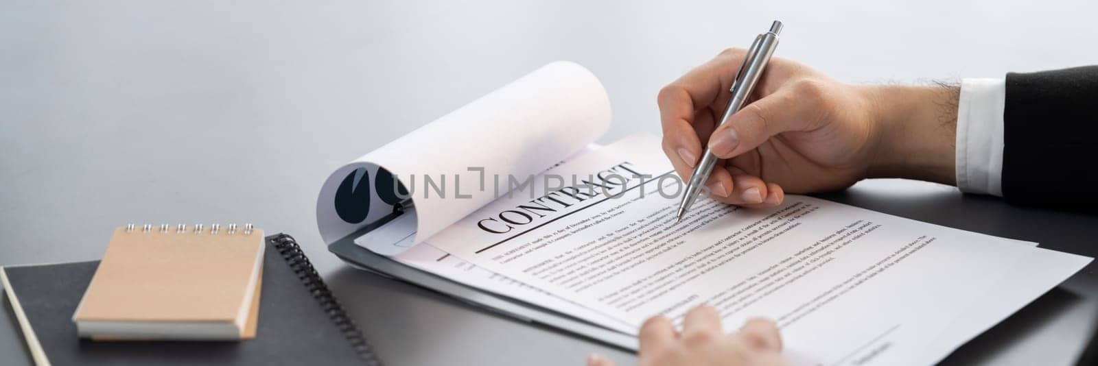 Businessman signs contract agreement paper or business legal form with trust and professionalism. Closeup of hand holding pen in corporate meeting for official business deal. Equilibrium