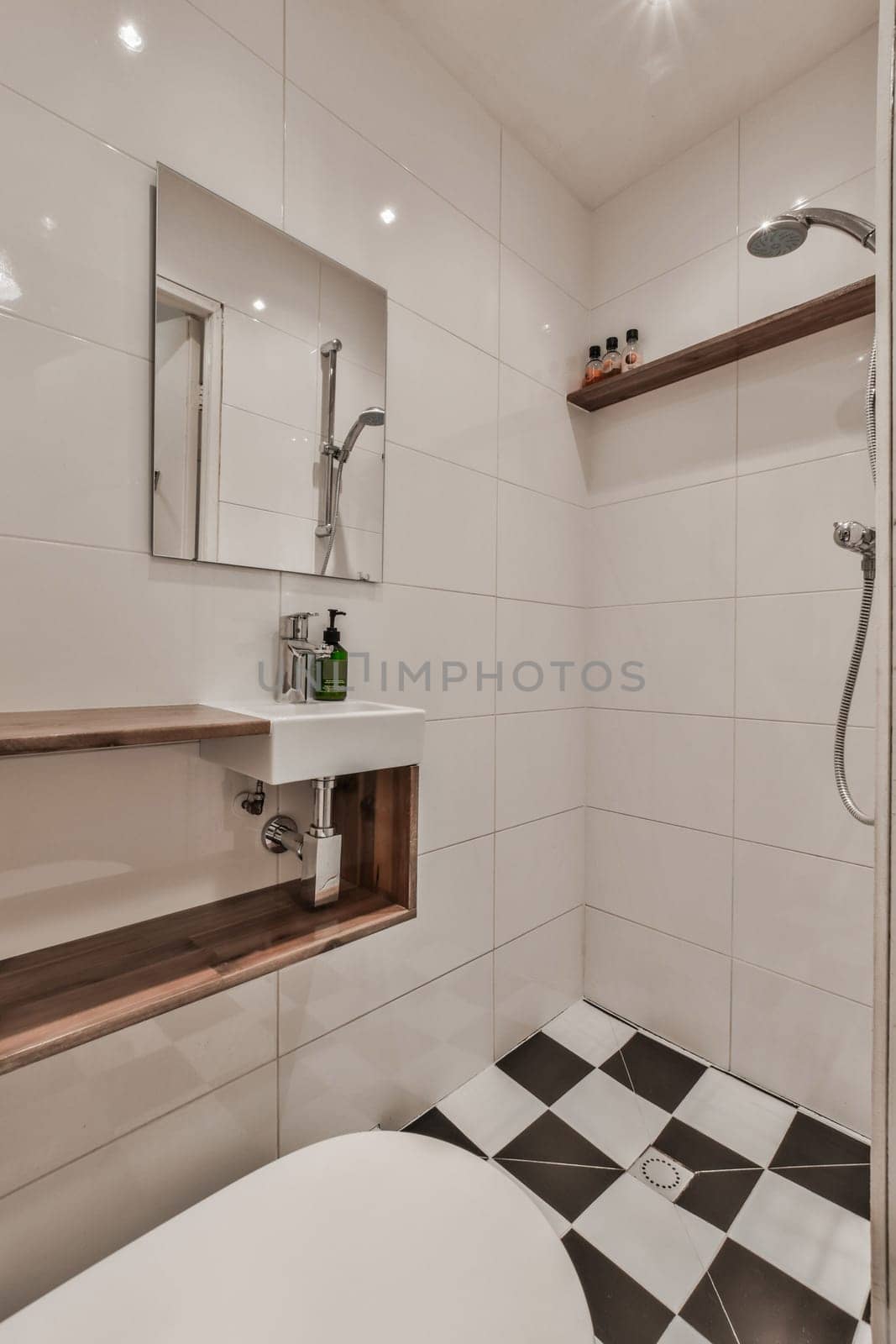 a modern bathroom with black and white tiles on the floor, sink, mirror, and shower head mounted to the wall