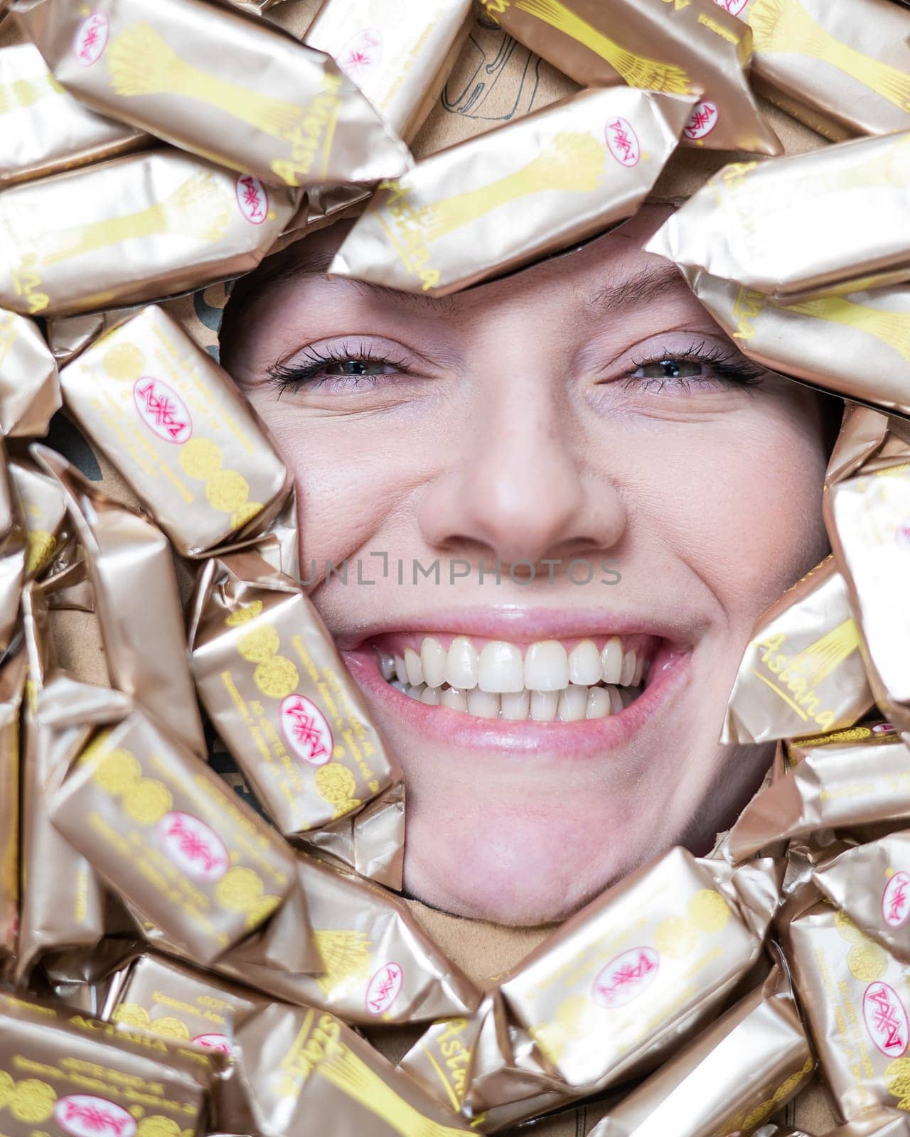 The face of a caucasian woman surrounded by Rakhat chocolates. by mrwed54