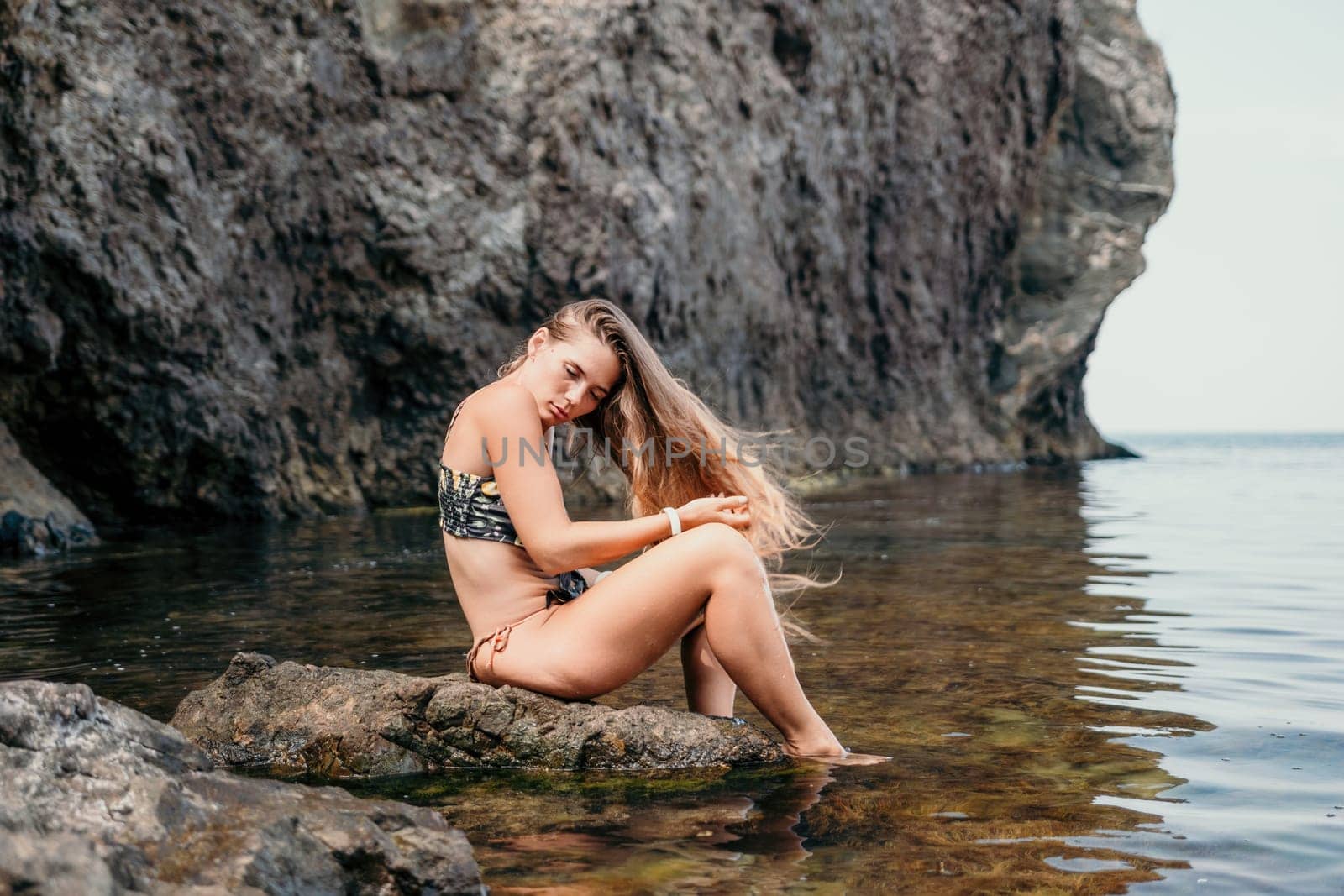 Woman travel sea. Happy tourist taking picture outdoors for memories. Woman traveler looks at the edge of the cliff on the sea bay of mountains, sharing travel adventure journey.