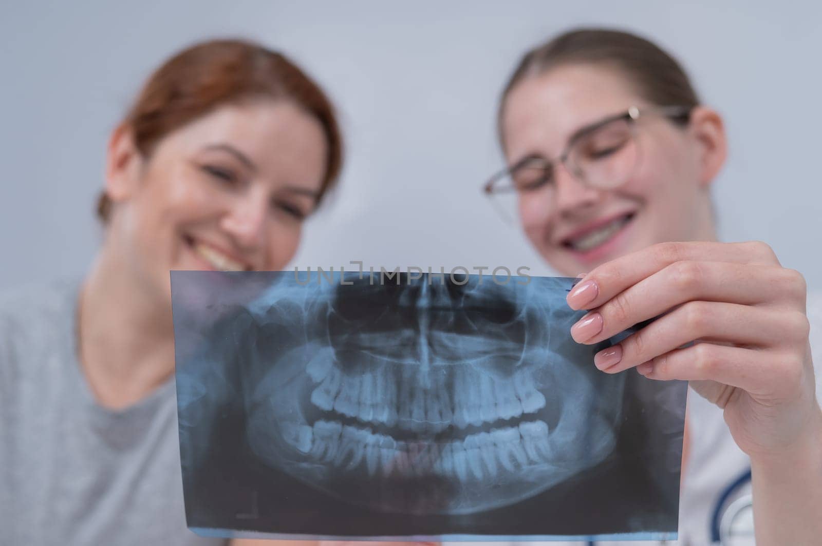 A woman doctor and a patient at the reception are discussing an x-ray of the jaw. by mrwed54