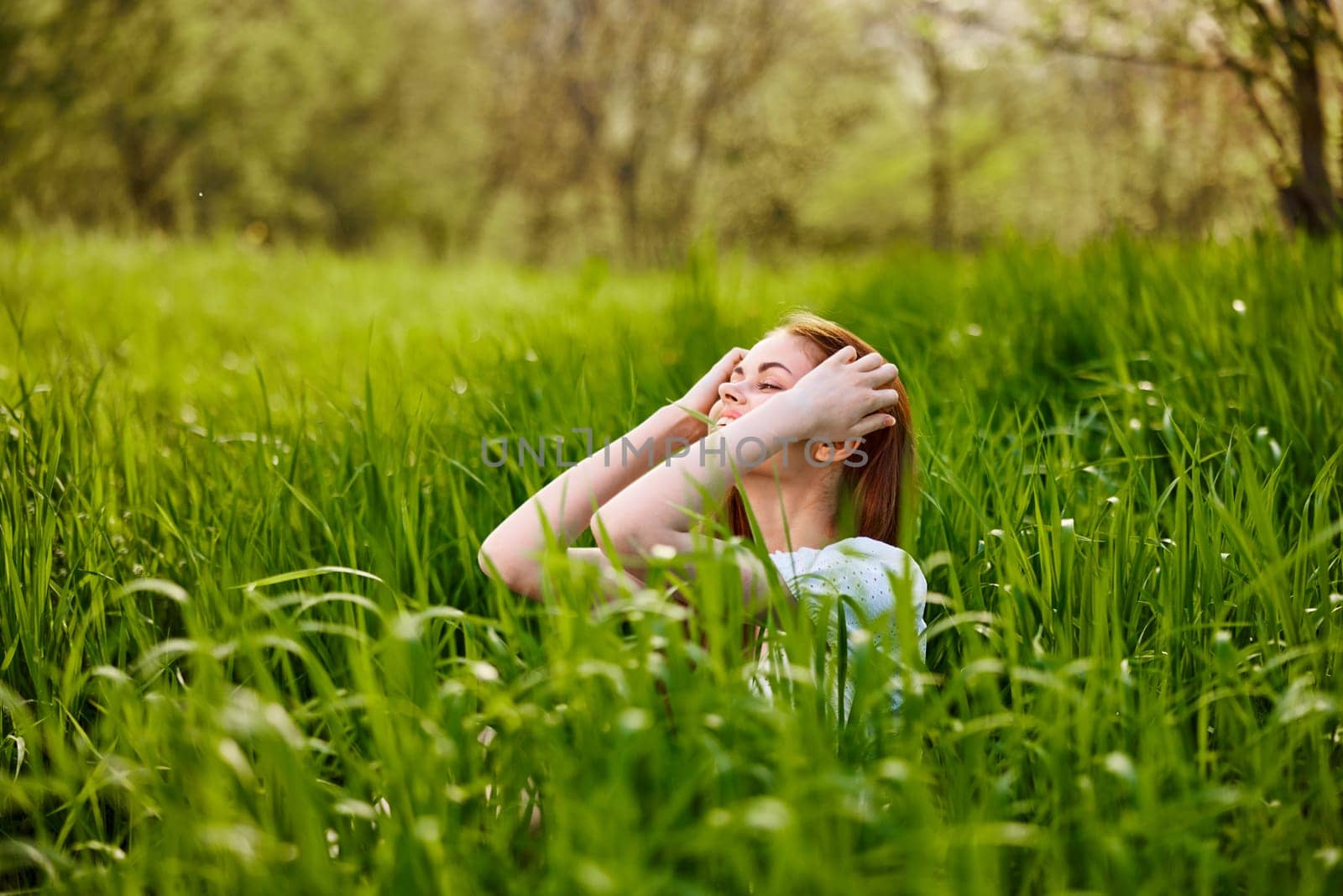 cute, contented woman sitting in tall green grass outdoors. High quality photo