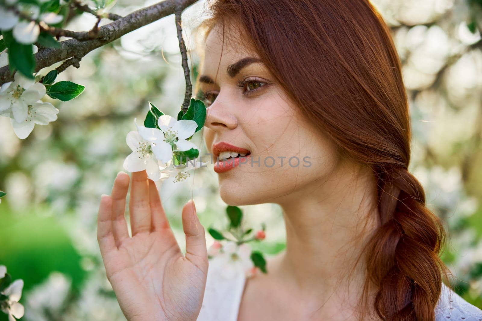 close portrait of a red-haired, laughing woman smelling flowers from a tree by Vichizh