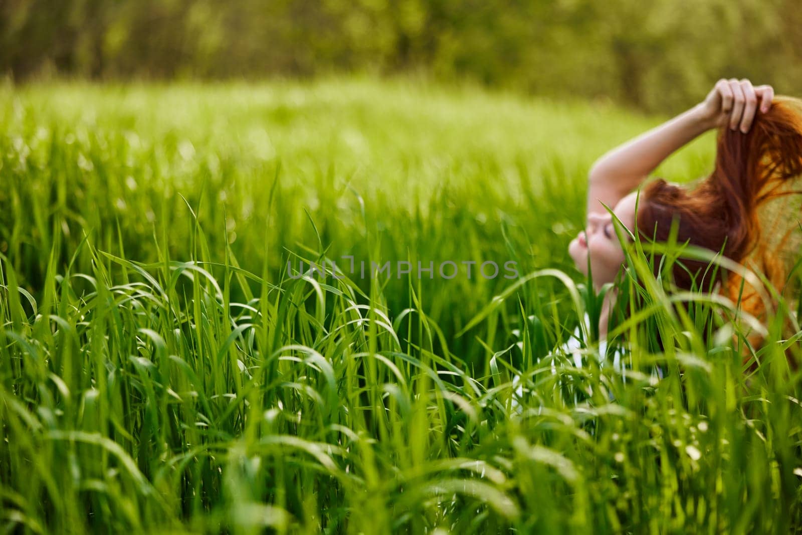 photograph of a woman sitting in the grass focusing on grass leaves by Vichizh