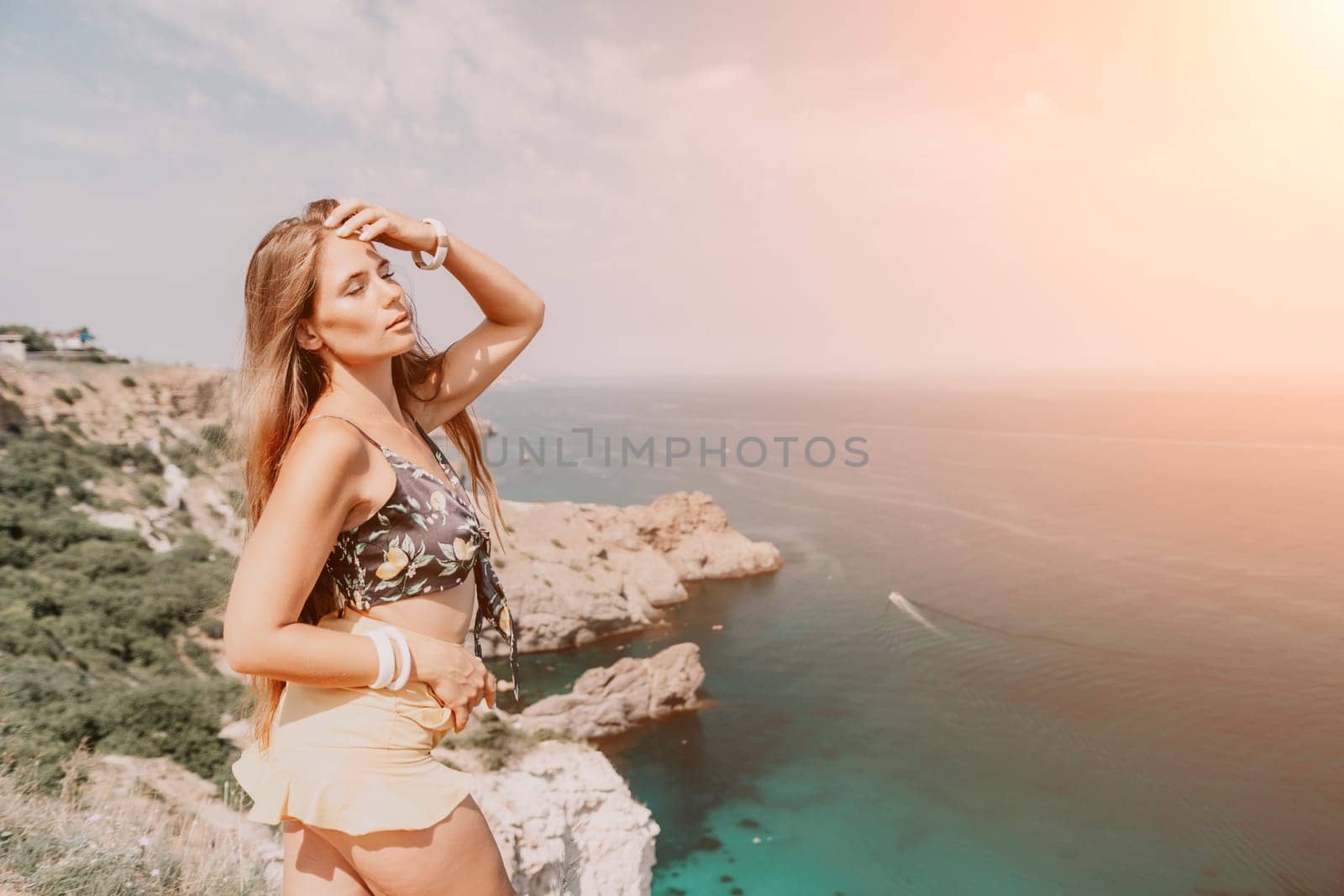 Woman travel sea. Happy tourist taking picture outdoors for memories. Woman traveler looks at the edge of the cliff on the sea bay of mountains, sharing travel adventure journey.