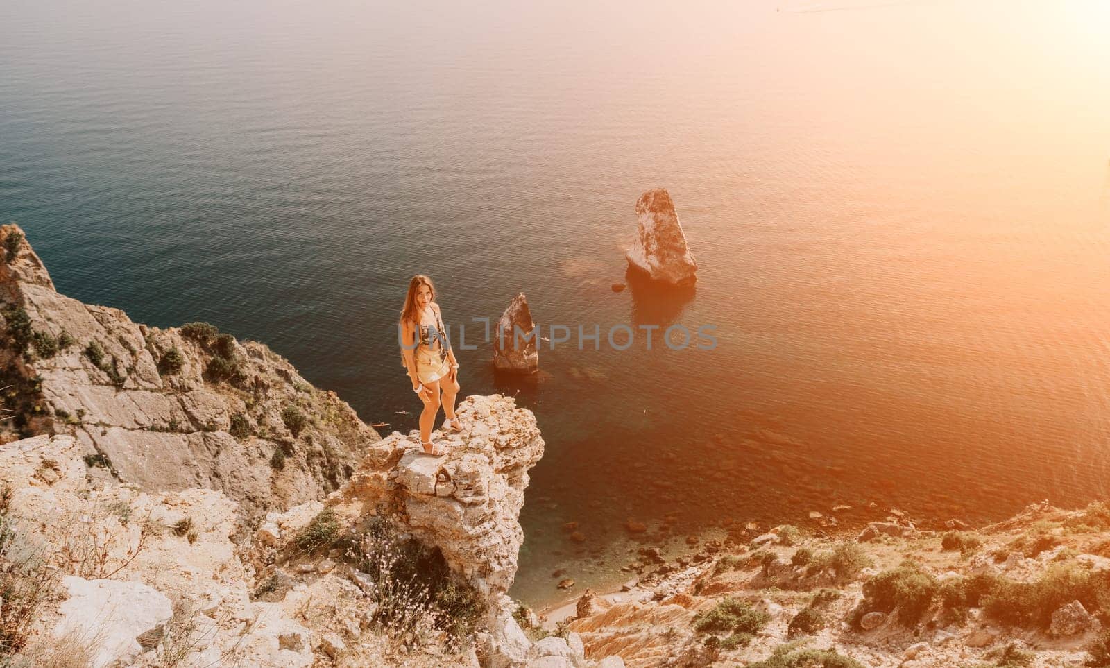 Woman travel sea. Happy tourist taking picture outdoors for memories. Woman traveler looks at the edge of the cliff on the sea bay of mountains, sharing travel adventure journey.