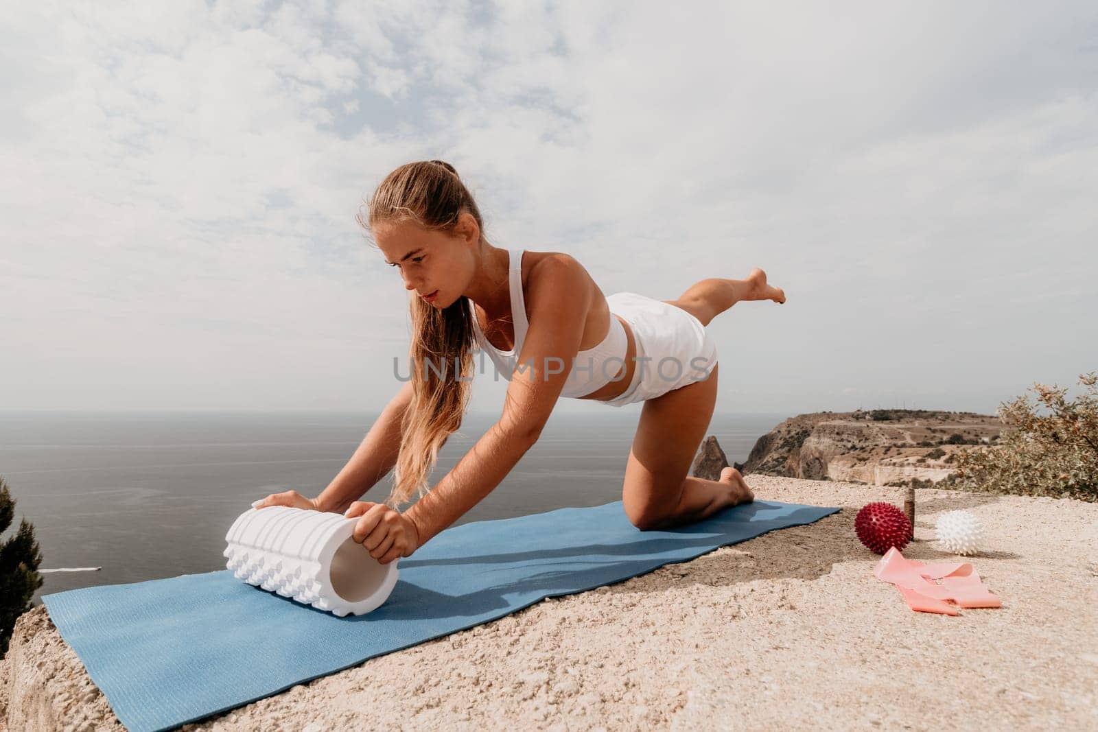 Woman sea pilates. Sporty, middle-aged woman practicing pilates in park near the sea. trains on a yoga mat and exudes a happy and active demeanor, promoting the idea of a healthy lifestyle through exercise and meditation.